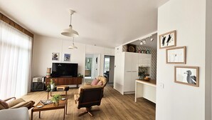 Un salon moderne avec un canapé, une table basse et un téléviseur. Il y a également un coin cuisine avec des placards et une table à manger.