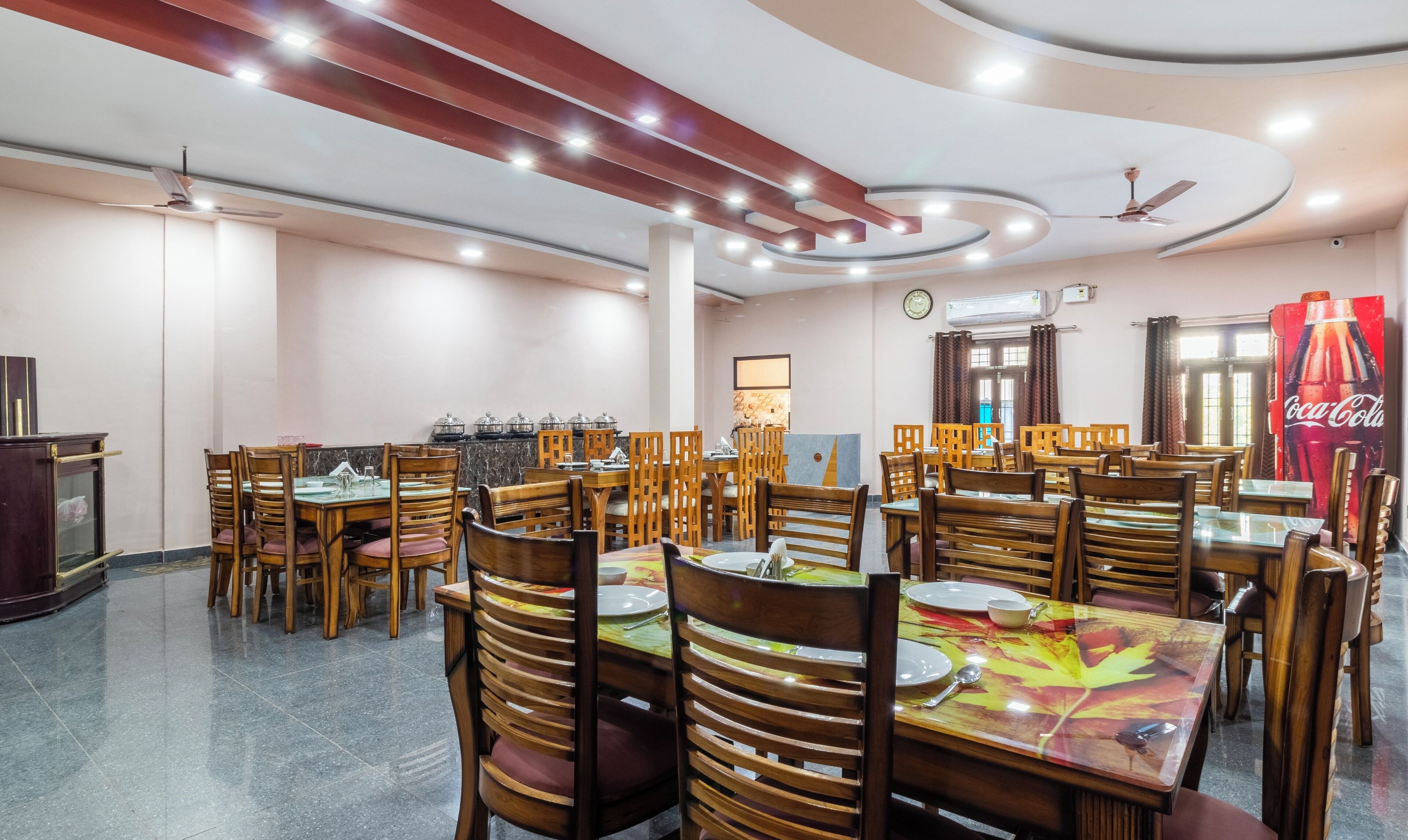 A spacious dining area with multiple tables and chairs, ceiling fans, and recessed lighting.