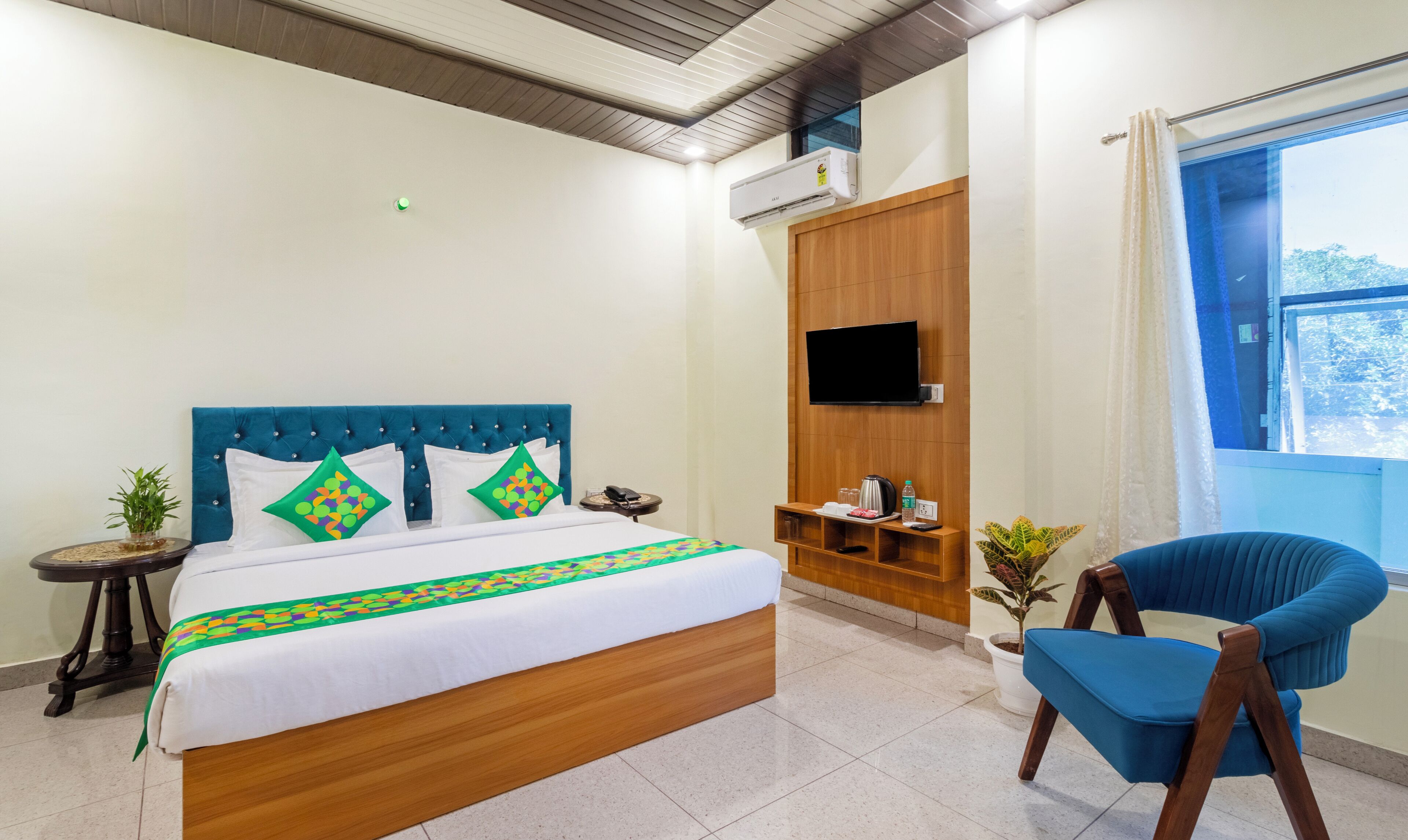 A hotel room with a bed, a TV, a chair, and a small table.