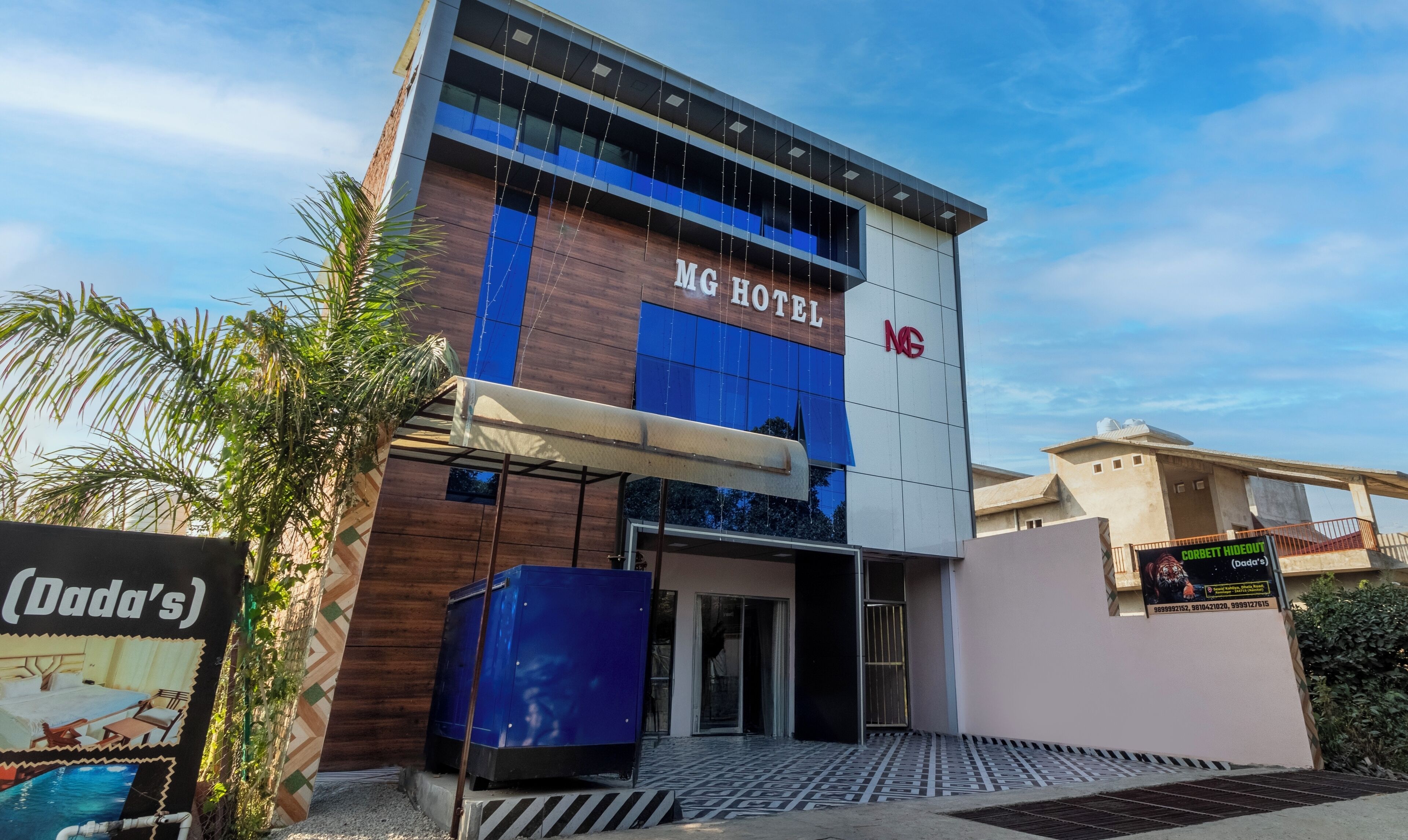Een modern hotelgebouw met een opvallend 'MG HOTEL' bord, een overdekte ingang en een zichtbaar 'Dada's' bord.