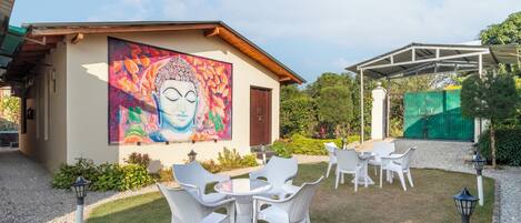 Un edificio con un mural de Buda, asientos exteriores y una zona cubierta.
