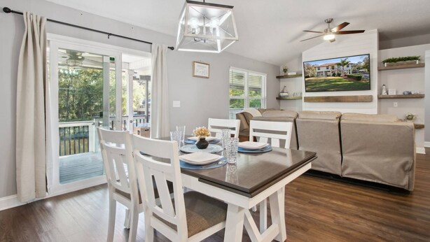 A modern living room with a dining area, a ceiling fan, and a large window with a view of greenery. - Waterfront 3BR Home | Private Boat Ramp & Firepit | 2 Small Dogs Welcome (Middleburg)