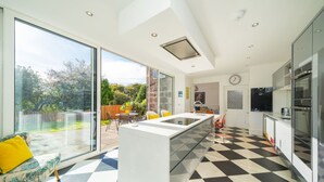 A modern kitchen with large windows, a dining area with a view, and a checkered floor. - Sunnybrae House Seaside Family-friendly Getaway in Stonehaven With Hot Tub (Stonehaven)