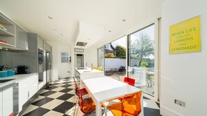 A modern kitchen with a checkered floor, a long white table, and red chairs. - Sunnybrae House Seaside Family-friendly Getaway in Stonehaven With Hot Tub (Stonehaven)