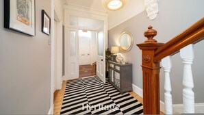 A hallway with a black and white striped floor, a wooden staircase, a mirror, and framed artwork on the walls. - Sunnybrae House Seaside Family-friendly Getaway in Stonehaven With Hot Tub (Stonehaven)