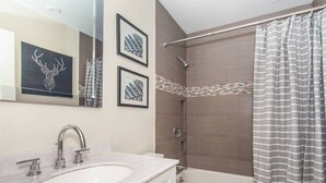 A bathroom with a sink, mirror, and shower. - Sleek Boston Condo | near South End (Boston)