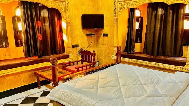 Una camera d'albergo con un letto grande, una televisione a parete e un pavimento a scacchi.