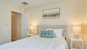 Una camera da letto con un letto grande, due abat-jour, un ingresso a un'altra stanza e un quadro appeso al muro.