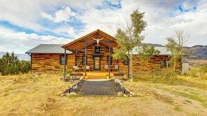 A log cabin with a porch, a fireplace, and a view of the surrounding landscape. - Colorado River Getaway in Parachute: Dogs Welcome! (Parachute)