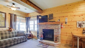 L'intérieur d'un chalet confortable, avec une cheminée, un canapé, un téléviseur et une table à manger.