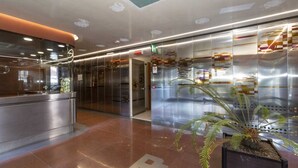 A modern lobby with a reception desk, glass partitions, and a potted plant.