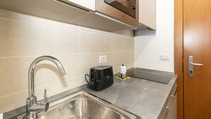 A compact kitchen with a stainless steel sink, a toaster, and a microwave.