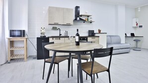 Una cucina moderna con tavolo da pranzo, sedie, forno a microonde, una bottiglia di vino e un divano.