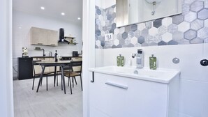 Una cucina moderna con zona pranzo, mobili bianchi e un rivestimento a mosaico esagonale.