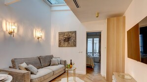 A modern living room with a sofa, a small round table, and a decorative rug. - TBS 204 - Prestigious suite near Champs-Élysées (Paris)
