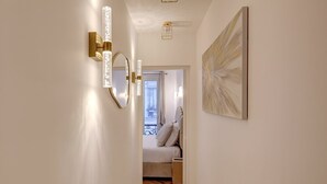 A hallway with a bed, a painting, and wall sconces. - TBS 204 - Prestigious suite near Champs-Élysées (Paris)
