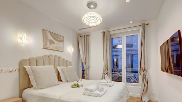 A hotel room with a bed, bedside tables, a chandelier, a window with curtains, and artwork on the walls. - TBS 204 - Prestigious suite near Champs-Élysées (Paris)