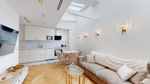 A modern kitchen with white cabinets, a dining area with a glass table, and a living room with a beige sofa. - TBS 204 - Prestigious suite near Champs-Élysées (Paris)