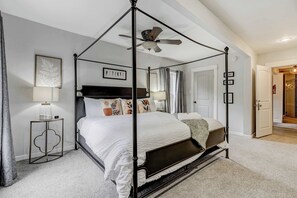 Un letto a baldacchino con ventilatore a soffitto, un comodino con una lampada e un quadro incorniciato appeso al muro.