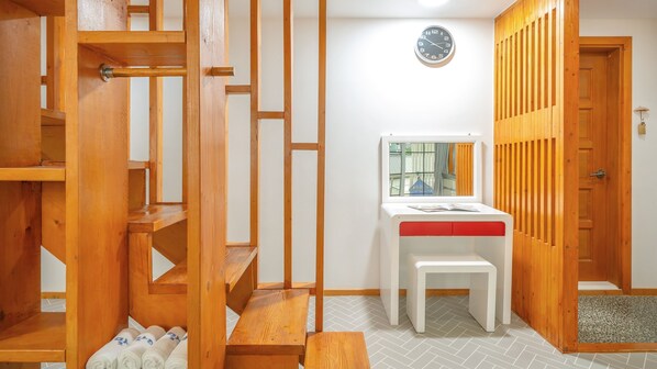 Una habitación con una escalera de madera, un banco blanco y un reloj en la pared.