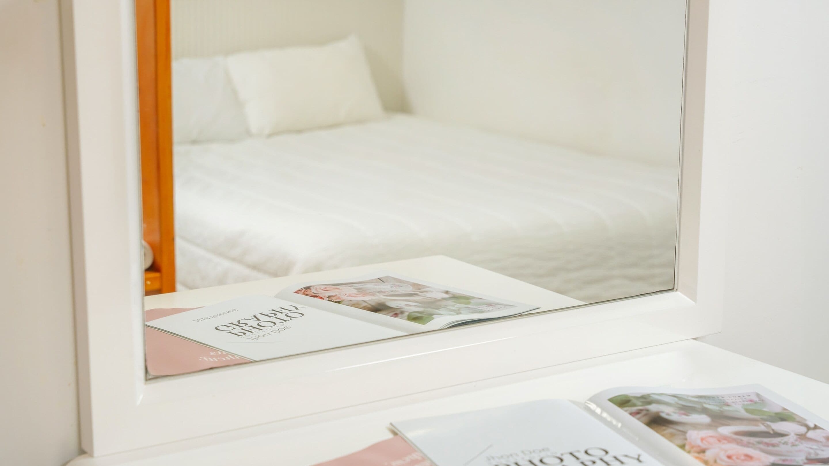 Ein Hotelzimmer mit einem Bett, einem Nachttisch und einem Spiegel, der das Bett wiederspiegelt.