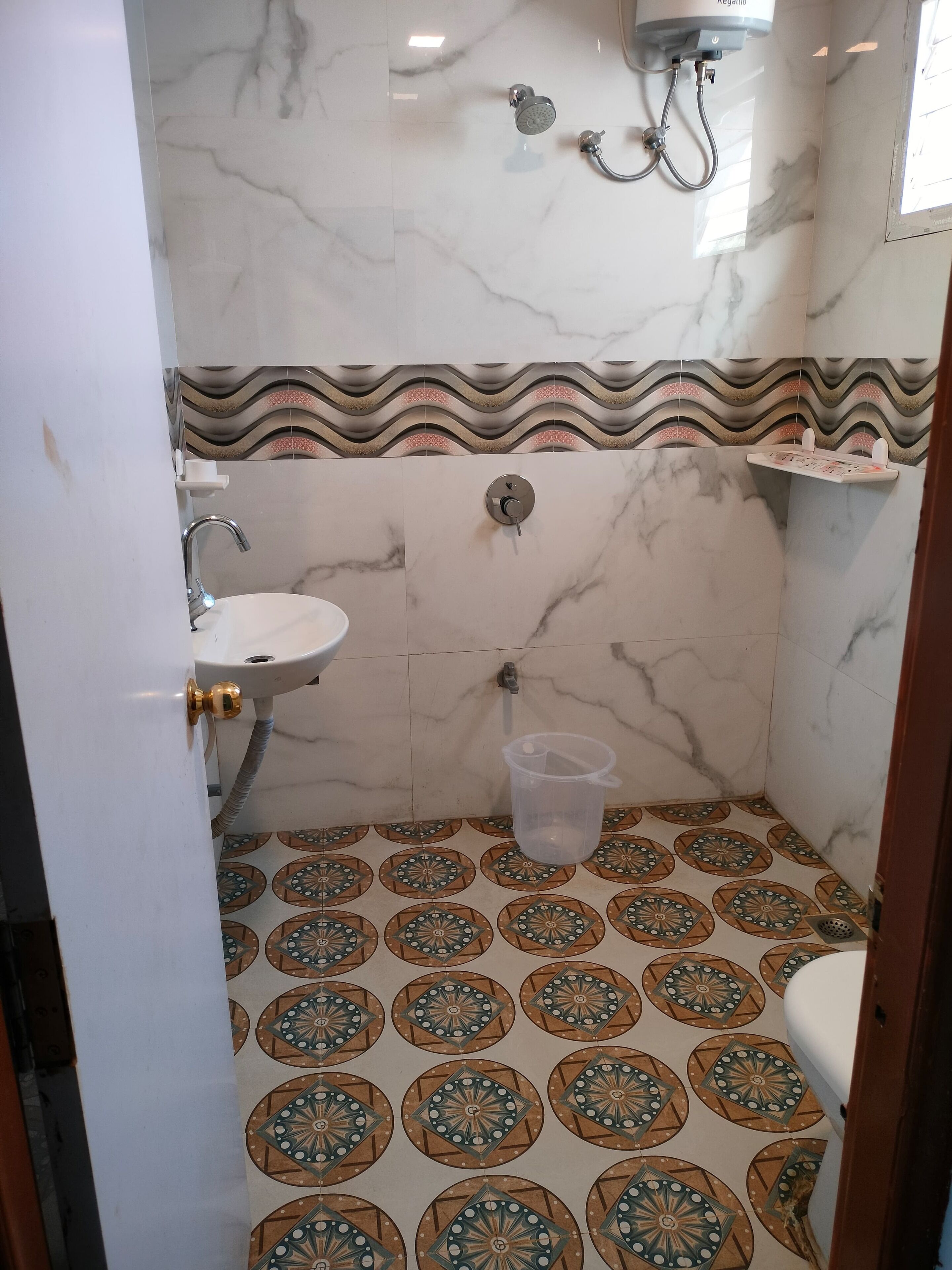 Un baño con lavamanos, ducha y baldosas de suelo con diseño.