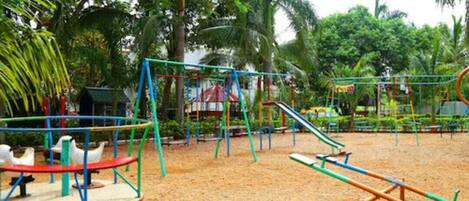 Un parque infantil con columpios, un sube y baja y un carrusel.
