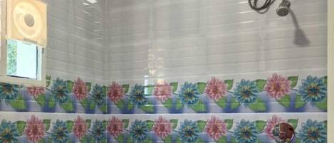 Un baño con azulejos blancos y azules a rayas, un inodoro y un calentador de agua en la pared.