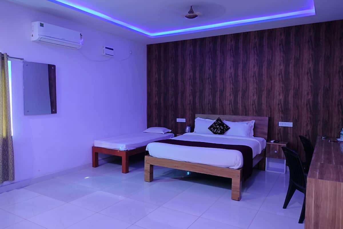 Habitación de hotel con dos camas individuales, un escritorio de madera y un diseño moderno de techo con iluminación azul.
