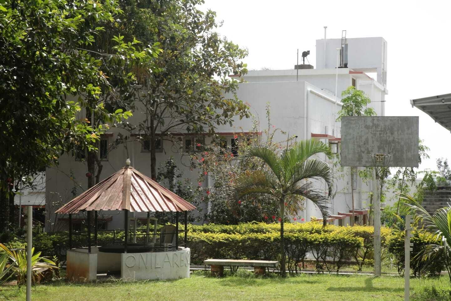 Um gazebo num jardim com um edifício ao fundo.