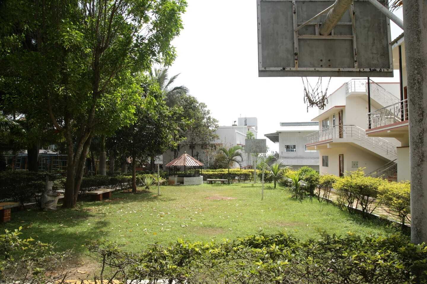 A courtyard with a gazebo, a basketball hoop, and a building with a balcony.