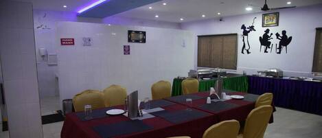 A conference room with a long table, yellow chairs, and a television screen.