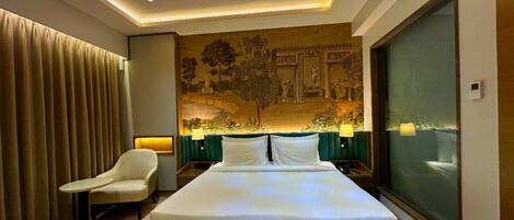 Una habitación de hotel moderna con una cama grande, una silla, un mural en la pared y un ventanal amplio.