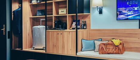 A hotel room with a bed, a TV, a wooden wardrobe, a suitcase, and a handbag.