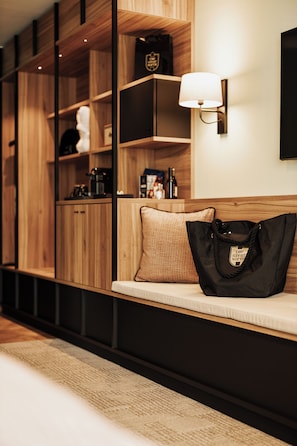 A hotel room with a wooden bench, a black bag, and a wall-mounted lamp. - The Great North - Hotel (Kaltenkirchen)