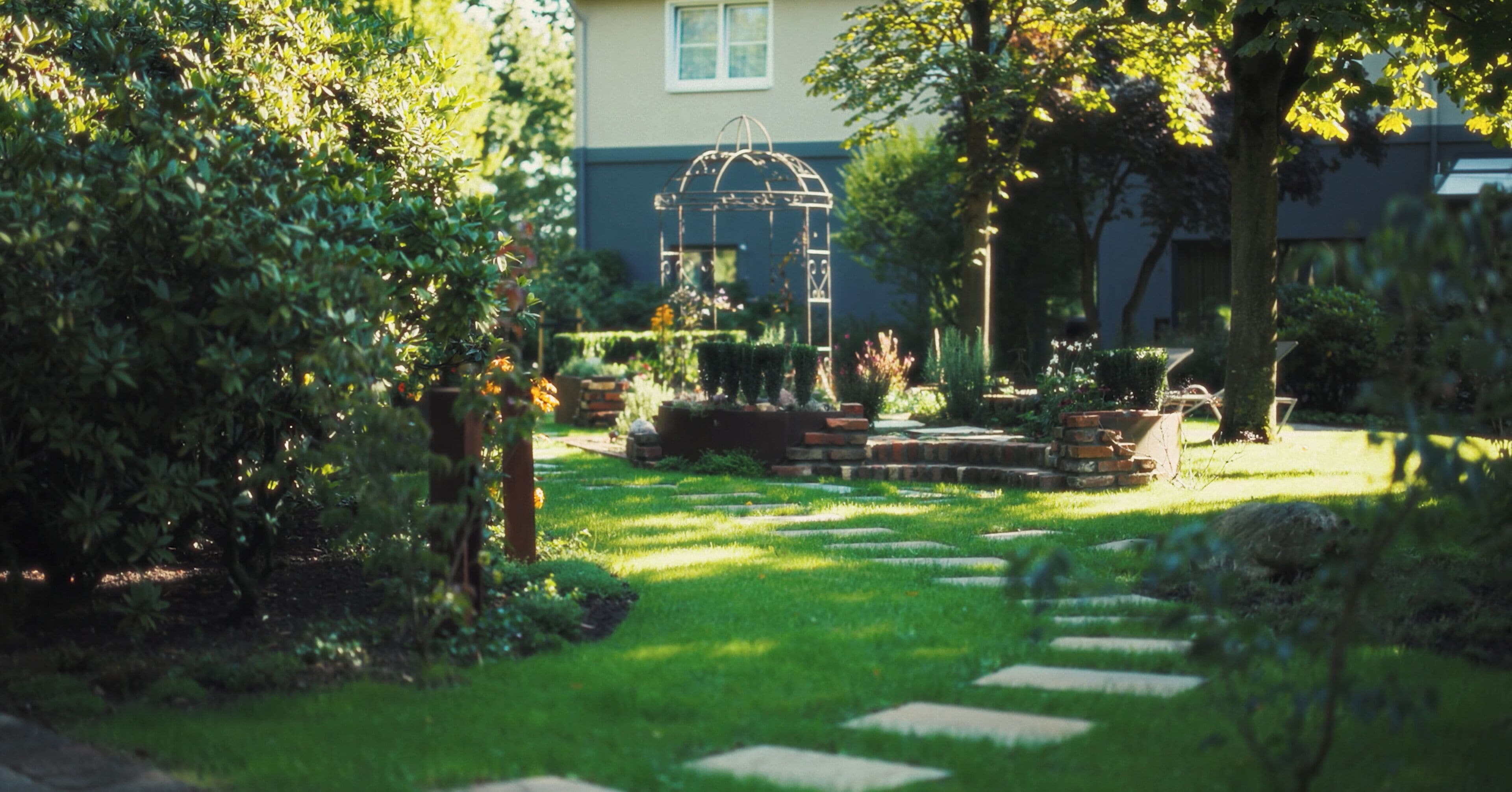 Un giardino con un vialetto in pietra che conduce a un gazebo.