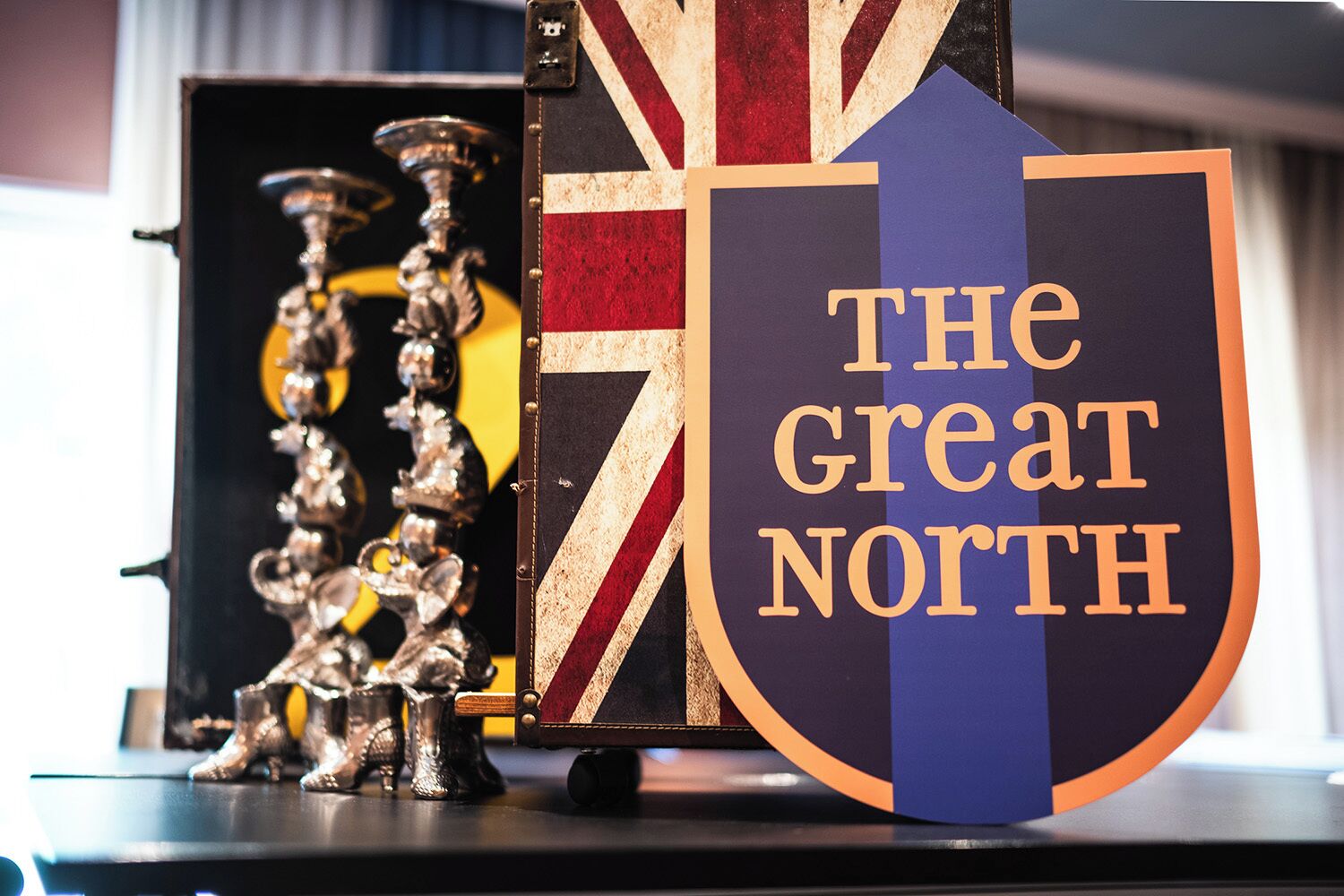 A shield-shaped sign with "THE GREAT NORTH" written on it, placed next to a decorative item with a Union Jack design.