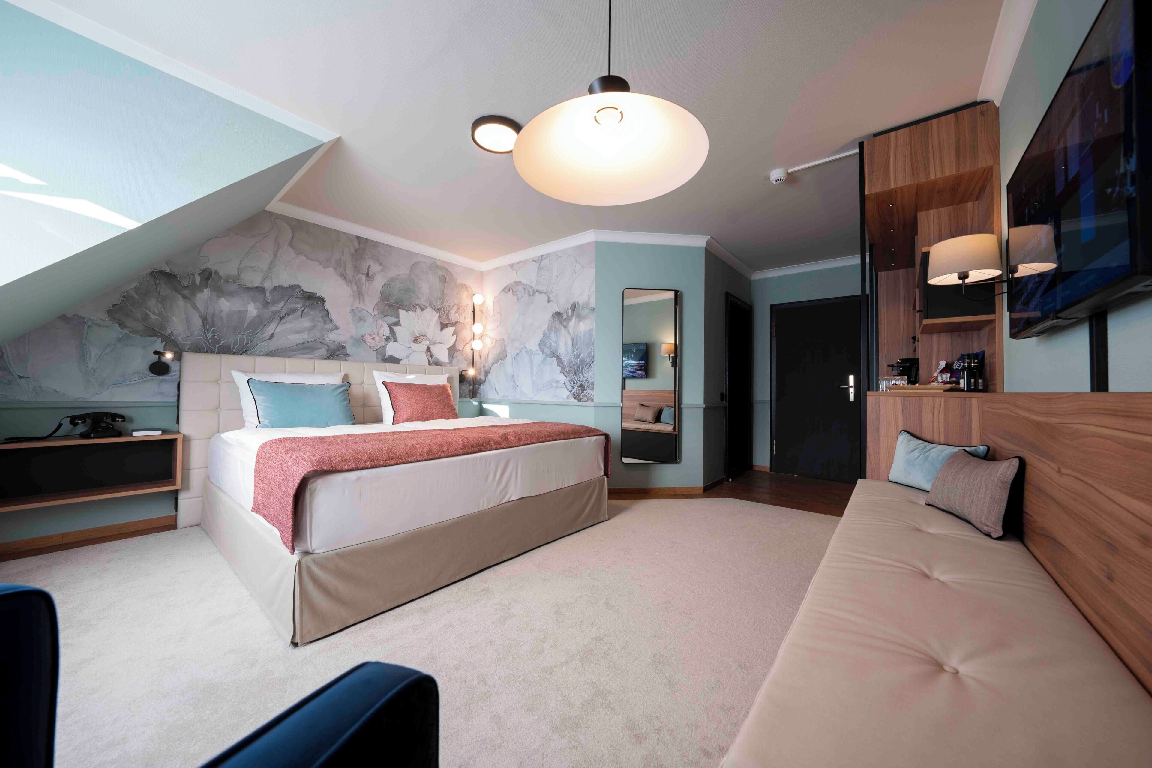 Un dormitorio moderno con cama, sofá, escritorio y un espejo grande.