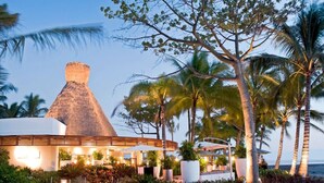 A resort with a thatched-roof building, palm trees, and a view of the ocean. - 3 Bedroom Spa Tower 5 Diamond VIP Golf Tournament VIP Park Access Vidanta World (Nuevo Vallarta)