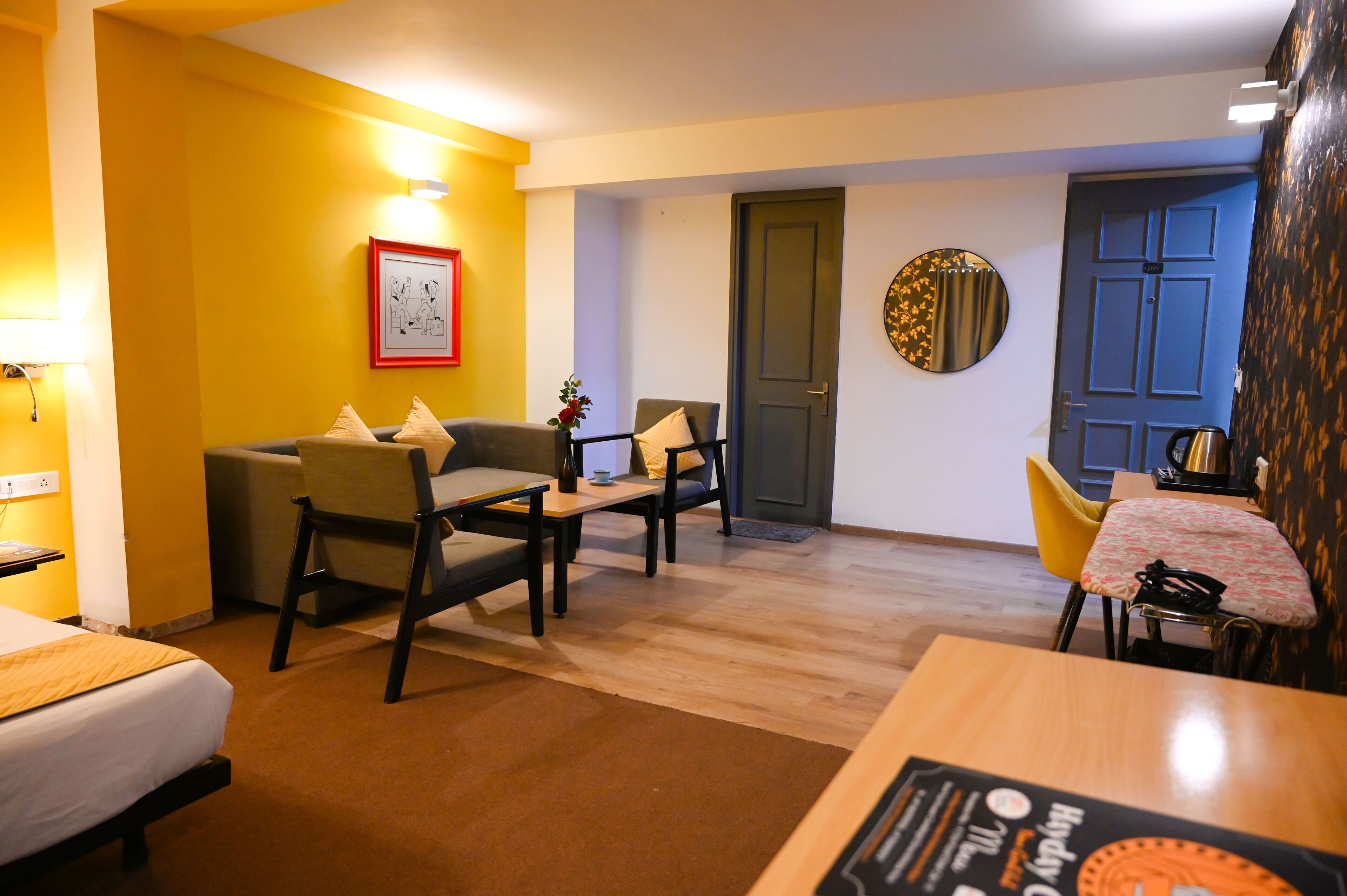 Ein Hotelzimmer mit einem Bett, zwei Sesseln, einem kleinen Tisch, einer Couch, einem Esstisch und einer Tür.