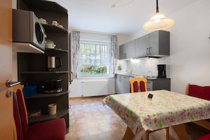 Una cocina compacta con una mesa de comedor, una ventana con cortinas y un radiador.