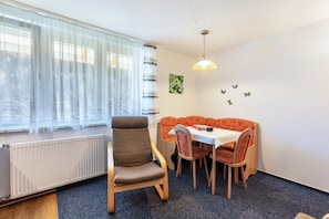 A dining area with a table and chairs, a radiator, a window with sheer curtains, and a wall with butterfly decals. - Apartment 'Appartement Nr 4' with Shared Terrace, Shared Garden and Wi-Fi (Todtmoos)