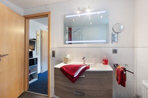 A modern bathroom with a vanity, mirror, towel rack, and a door leading to a hallway. - Apartment 'Appartement Nr 5' with Shared Terrace, Shared Garden and Wi-Fi (Todtmoos)