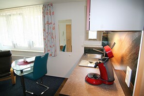 A compact kitchen with a red coffee maker, a glass table, and a blue chair. - Apartment 'Appartement Nr 5' with Shared Terrace, Shared Garden and Wi-Fi (Todtmoos)