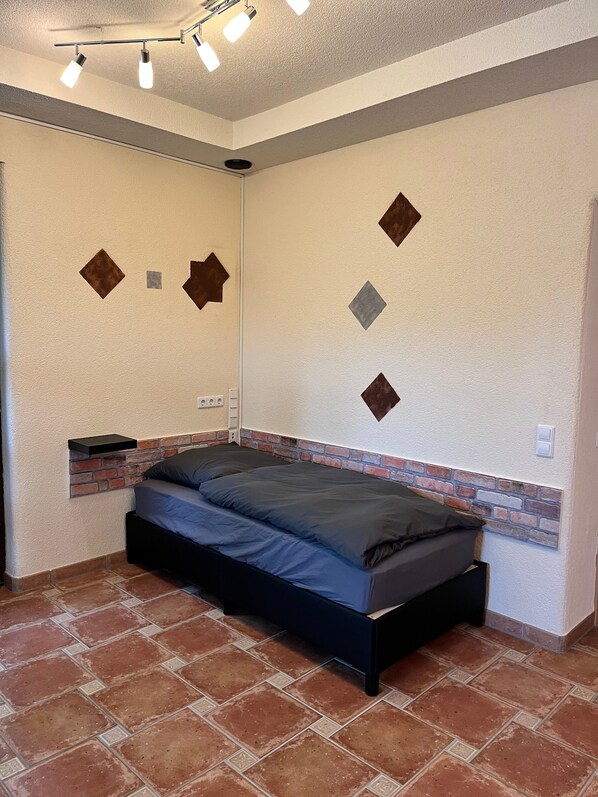 Ein Schlafzimmer mit einem Bett, einer Ziegelwand als Akzent und einer Deckenleuchte.