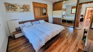 Ein modernes Schlafzimmer mit einem großen Bett, einem Holzkopfteil und einem Spiegelkorpus.
