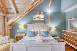 A bedroom with a bed, nightstands, a dresser, and a ceiling with exposed beams.