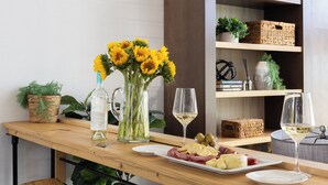 A wooden bar area with a wine bottle, a pitcher of water, a vase of sunflowers, and plates of food. - Paso Vista Bella by AvantStay | Luxe Group Escape w/ Wine Country Views (Paso Robles)