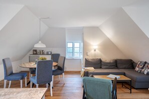 A loft-style apartment with a dining area, a sofa, and a small table.