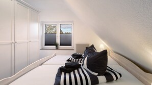A bedroom with a bed, a window with blinds, and a radiator.